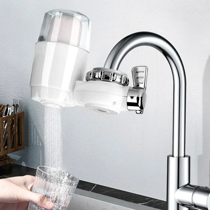 Kitchen faucet with a water filter attachment and a glass being filled with water.